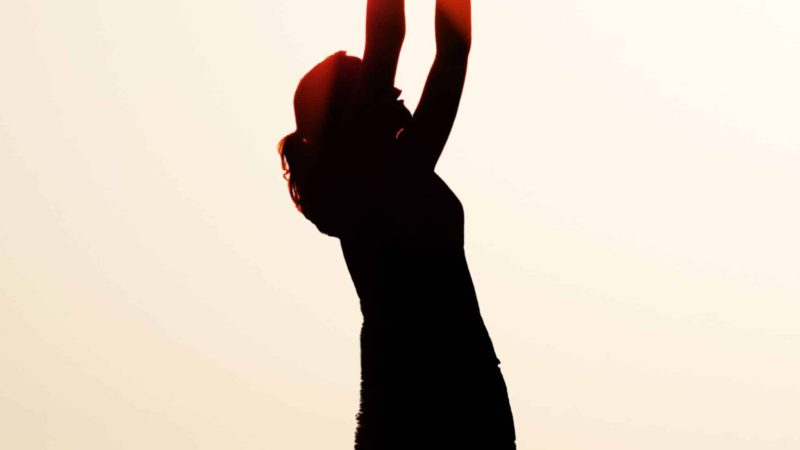 A photo of a healer with hands raised in the air seeking communication from the ancestors during divination.