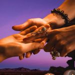 An image showing a world healers member holding the hand of a client during a palm reading session